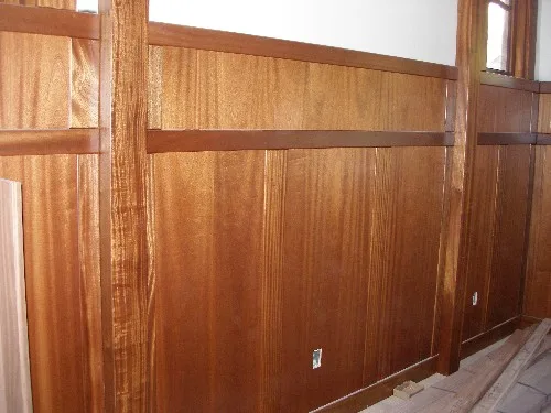 Reddish-brown Sapele mahogany wall paneling with wide boards between square posts and a horizontal rail